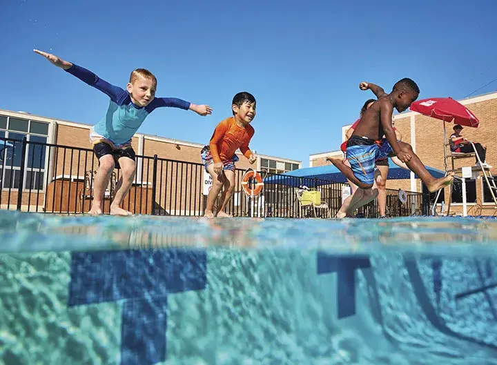 three children jumping into an outdoor pool