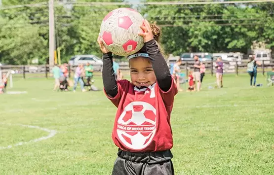 A girl holds a soccer ball at a YMCA class